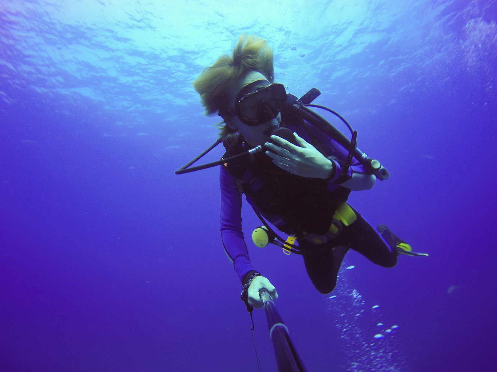 Underwater scuba diving selfie shot with selfie stick. Deep blue